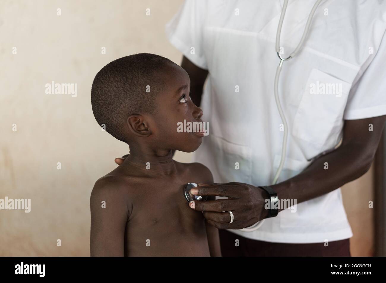 Operatore sanitario che esamina il battito cardiaco di un ragazzo nero con un piccolo sguardo sicuro con uno stetoscopio Foto Stock