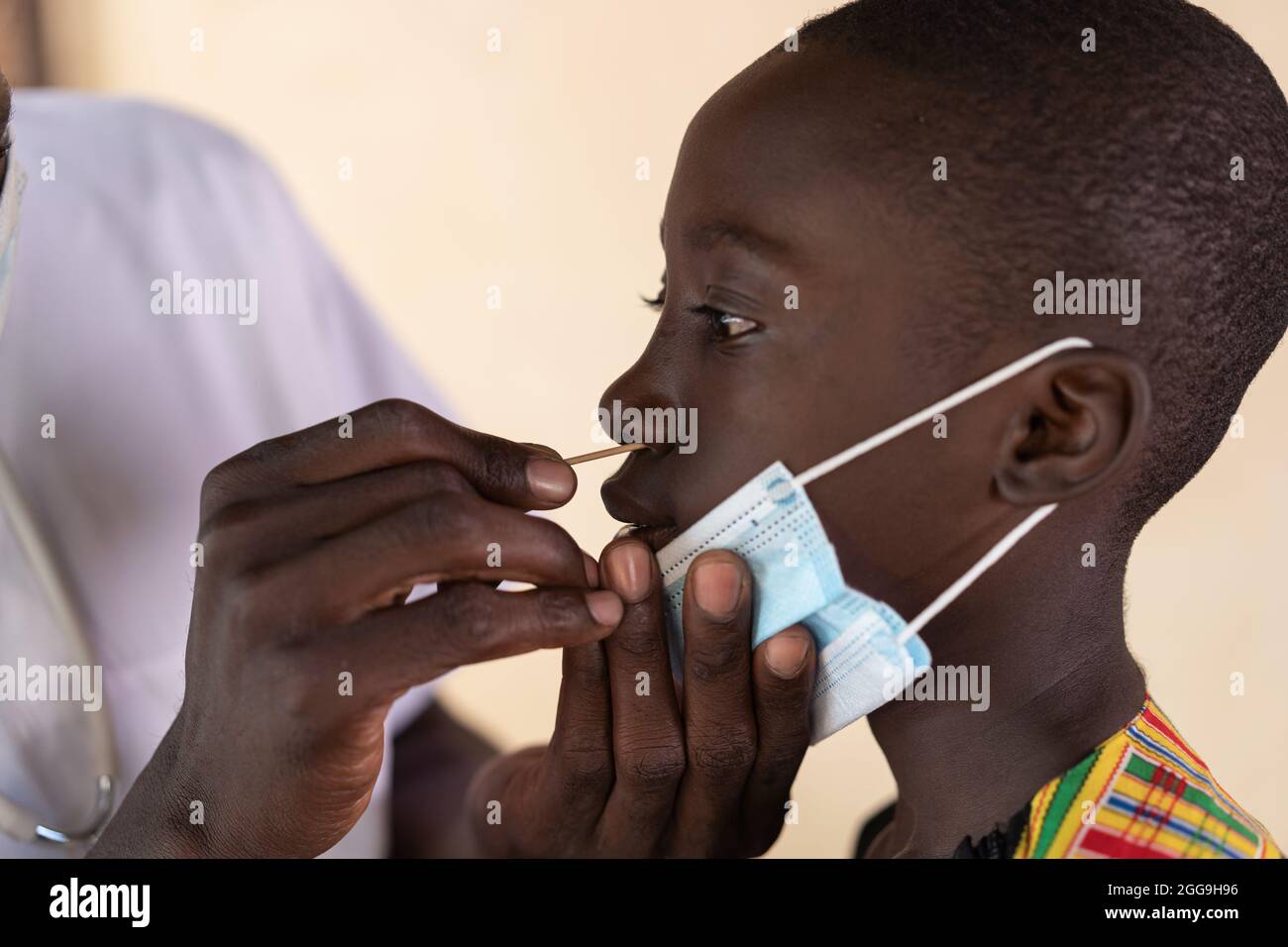 Primo piano di uno scolaro nero sottoposto a test con tampone nasale durante lo screening della corona in una scuola africana Foto Stock