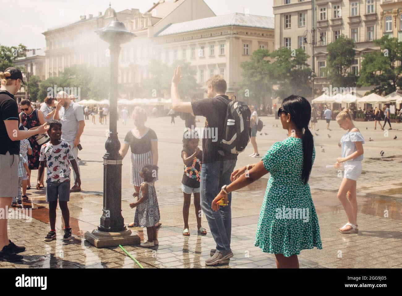CRACOVIA, POLONIA - 21 luglio 2019: Sistema di acqua nebulizzata per il raffreddamento in una piazza principale di Cracovia nelle calde giornate estive, i turisti sono vicini all'appannamento Foto Stock