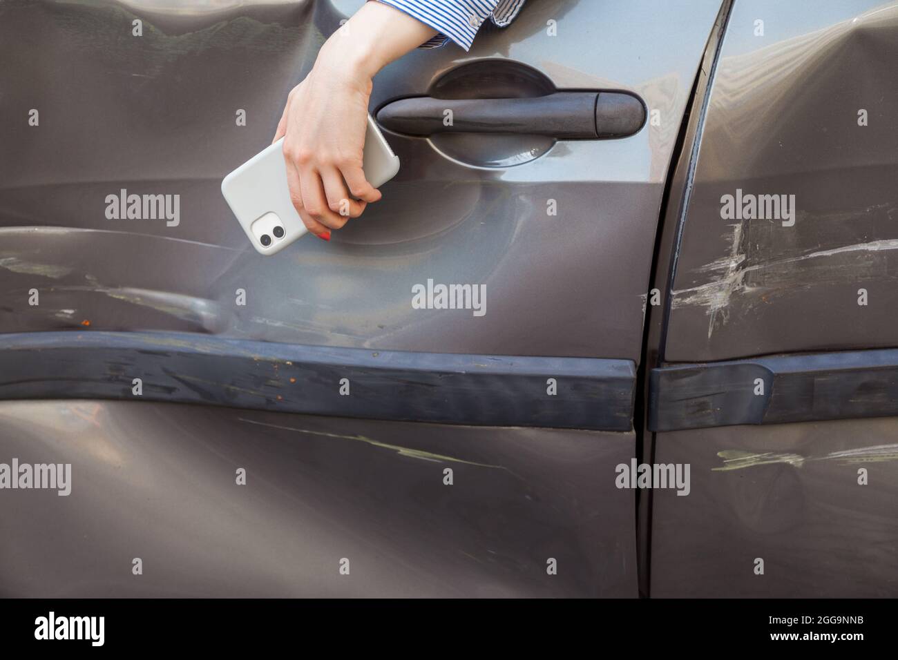 Donna sconosciuta in auto schiantata, donna senza volto con la mano appesa dalla finestra dell'automobile danneggiata, persona ferita in veicolo schiacciato. Scatto all'aperto. Foto Stock