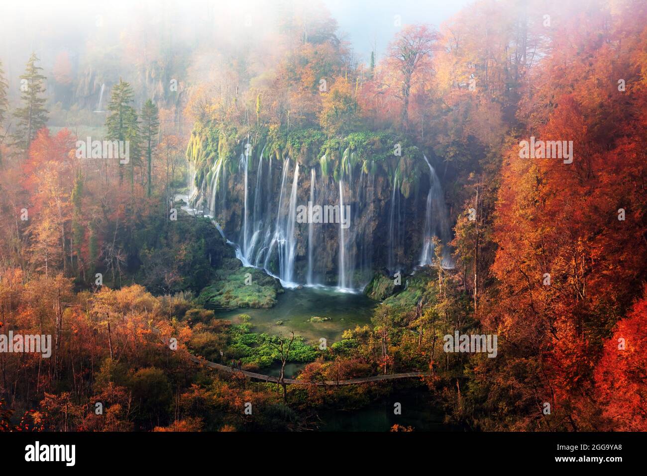 Incredibile vista sulla cascata delle nebbia nei laghi di Plitvice. Arancio autunno foresta sullo sfondo. Parco Nazionale di Plitvice, Croazia. Fotografia di paesaggio Foto Stock