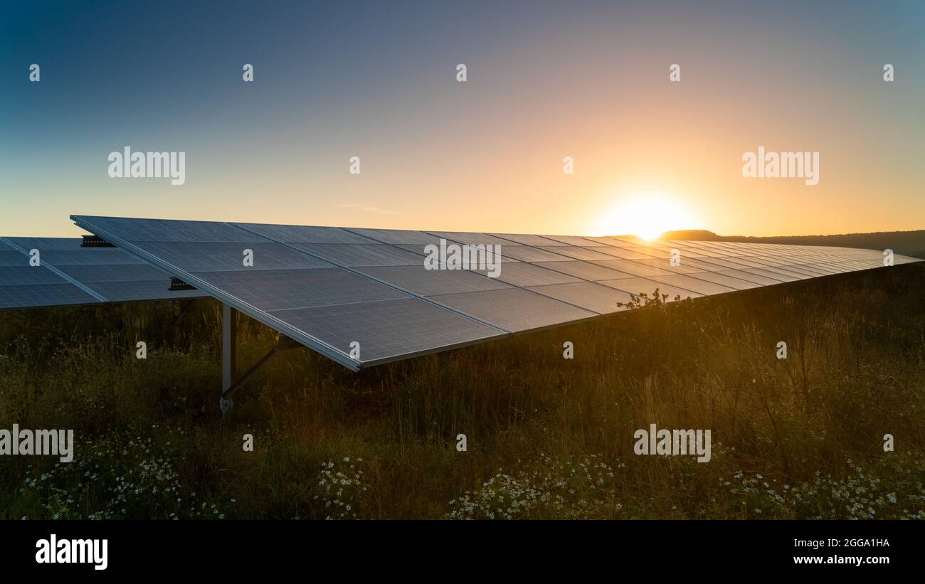 Il sole si imposta sulla fattoria di energia solare Foto Stock