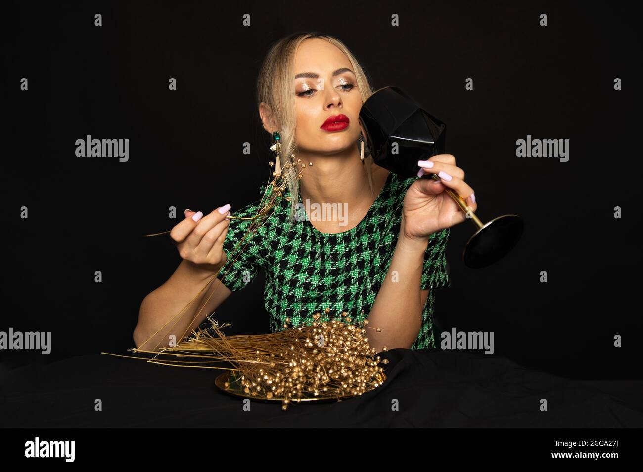 Dieta in oro nuziale per la giovane donna bionda di lusso in abito verde su sfondo nero è annoiato sulla dieta. Concetto di disturbo alimentare. Foto studio Foto Stock