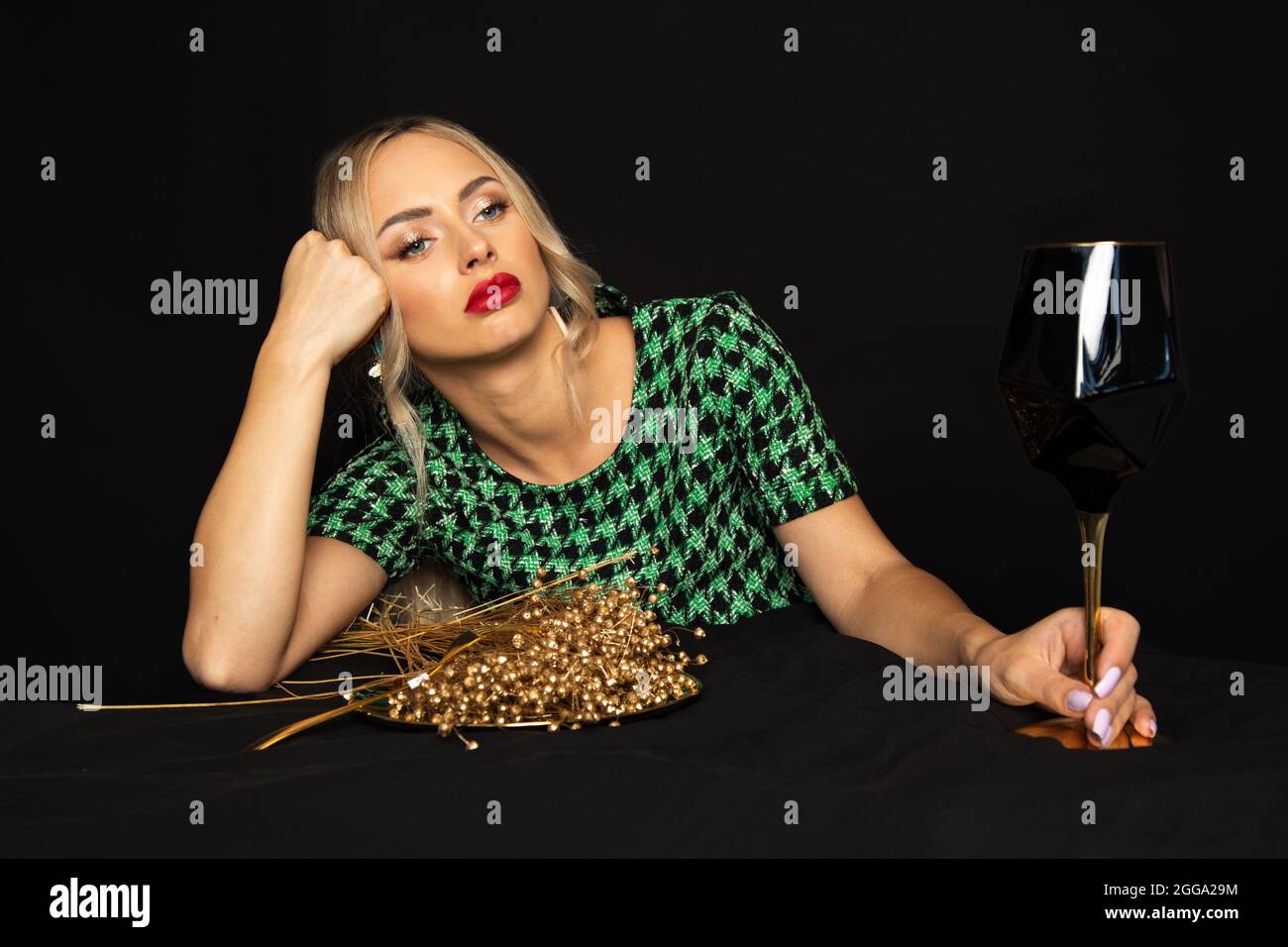 Lussuosa giovane donna bionda in abito verde su sfondo nero è annoiato sulla dieta. Concetto di disturbo alimentare. Foto Stock