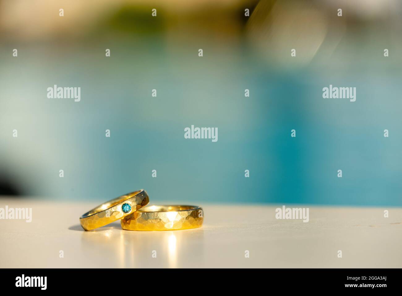 Un paio di anelli d'Oro per matrimoni con Turquoise Diamond di fronte ad una piscina dell'hotel Foto Stock