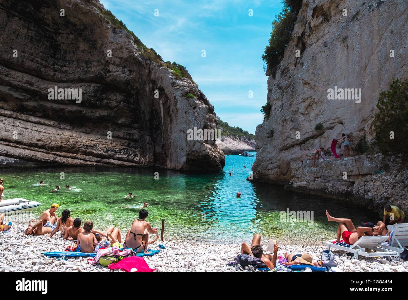 Stiniva Croazia, luglio 2021 splendida spiaggia di Stiniva sull'isola di Vis. Teal mare adriatico, cielo blu in lontananza. Spiaggia piena di p. Foto Stock