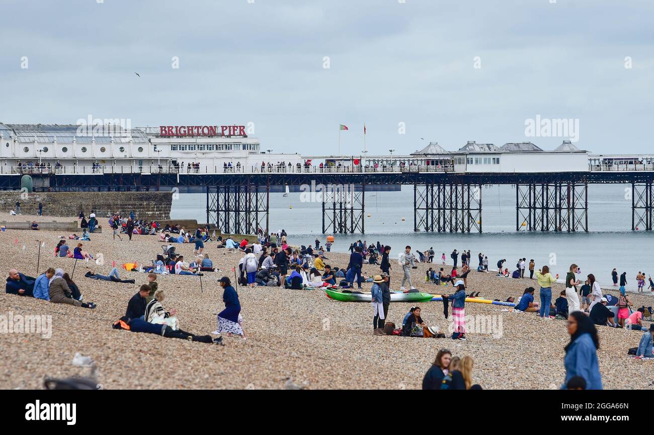 Brighton UK 30 Agosto 2021 - visitatori sulla spiaggia di Brighton vicino al molo nonostante il tempo nuvoloso delle vacanze bancarie di agosto . : Credit Simon Dack / Alamy Live News Foto Stock
