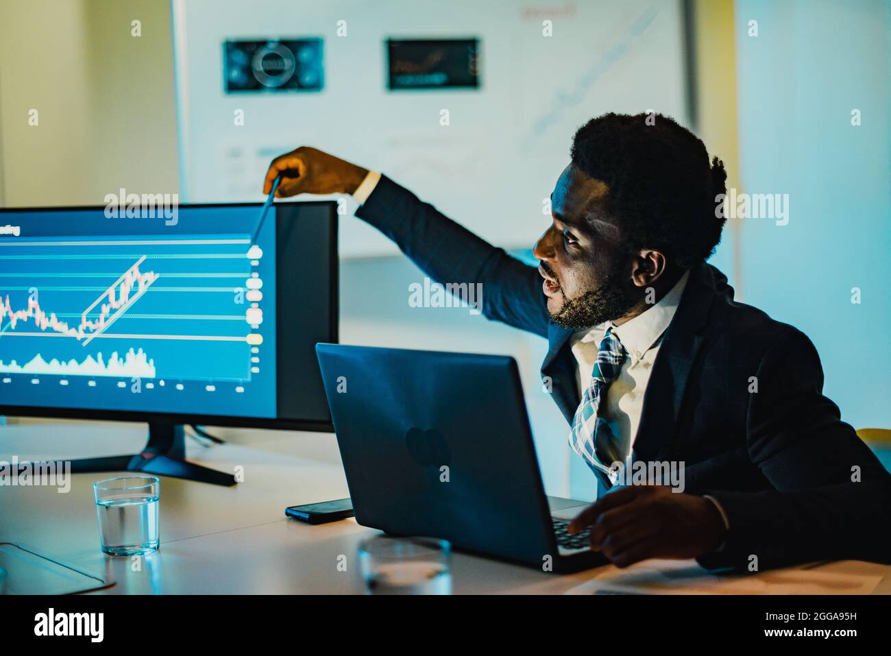 L'uomo africano che fa l'analisi della criptovaluta all'interno della banca - Focus on Face Foto Stock