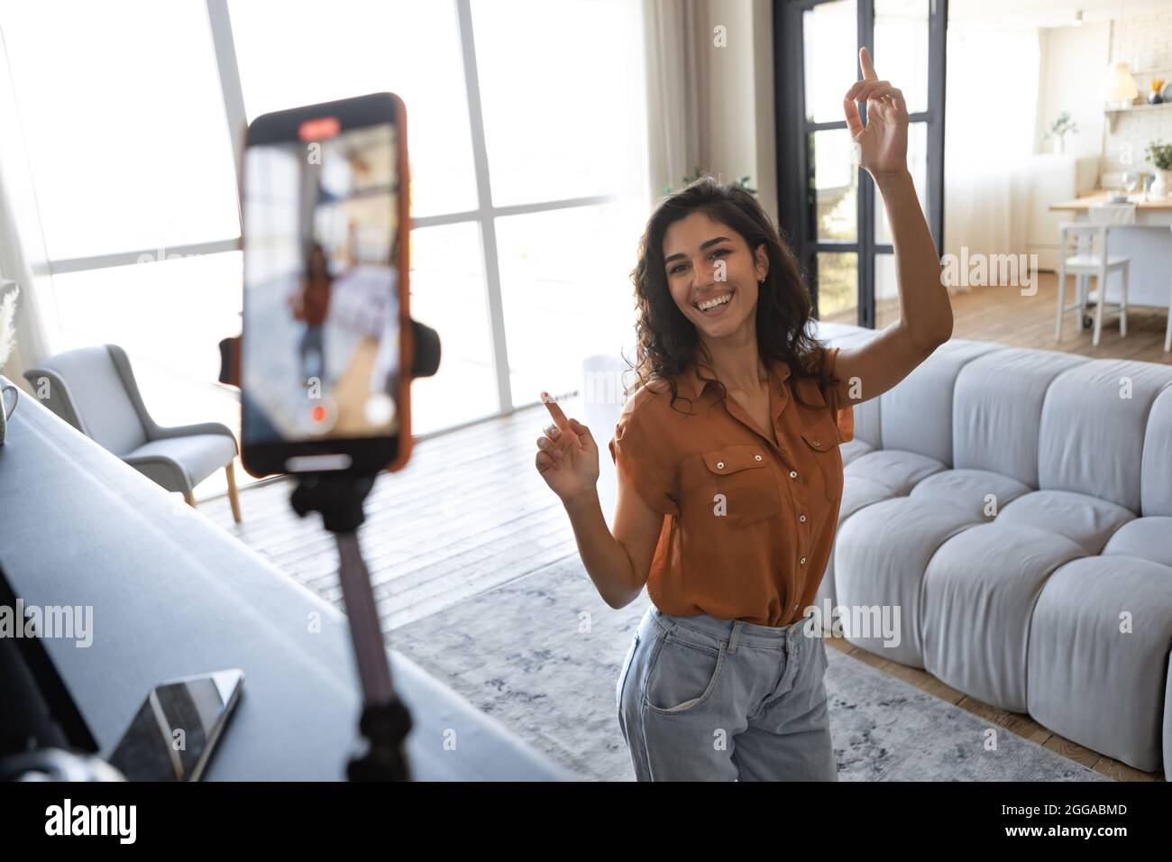 Allegra influencer femminile che spara video dance per i social media sul telefono cellulare, divertendosi a casa Foto Stock