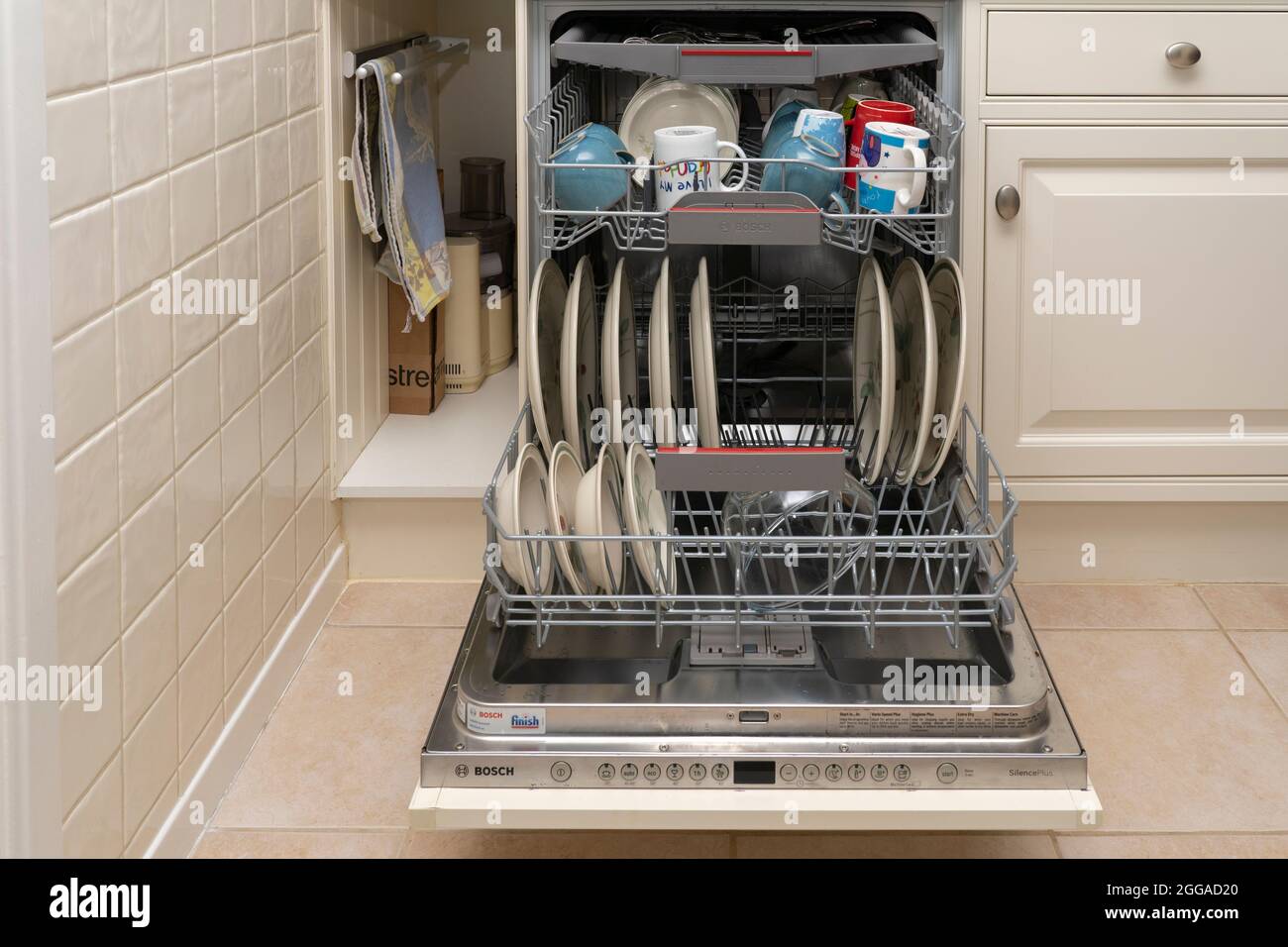 Una lavastoviglie completa piena di piatti lavati, tazze e stoviglie in una cucina domestica a casa Regno Unito, Gran Bretagna Foto Stock