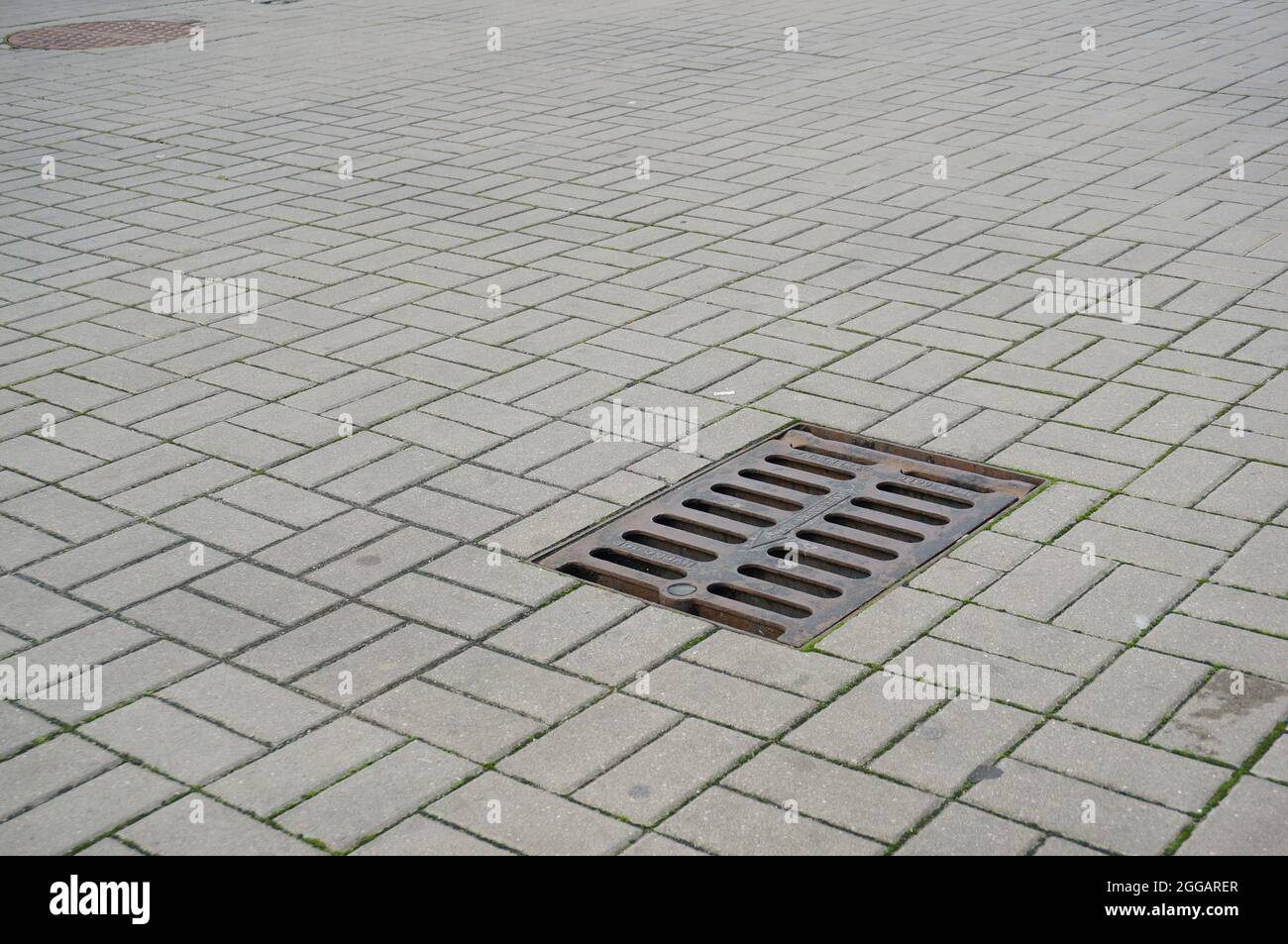 Manhole sul marciapiede con piastrelle di pietra Foto Stock