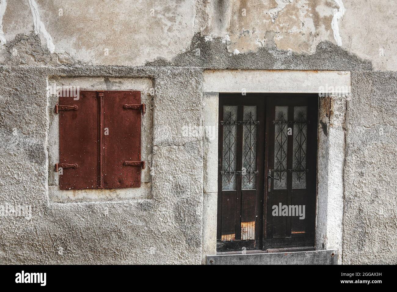 serramento arrugginito e porta di legno in un muro di una casa adriatica Foto Stock