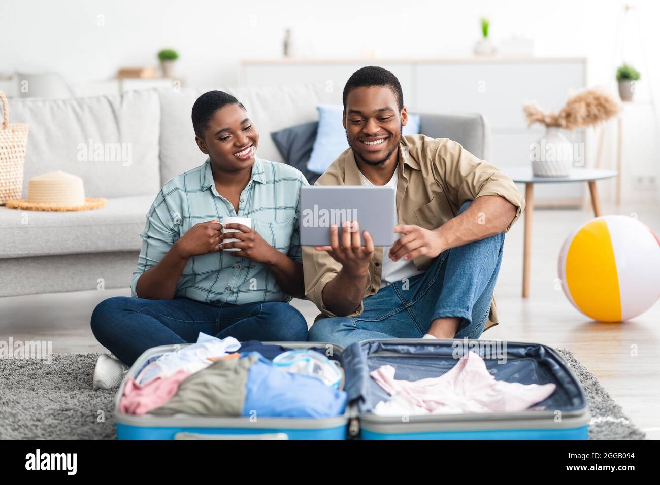 Felice coppia di turisti afroamericani che utilizzano il Tablet digitale a casa Foto Stock