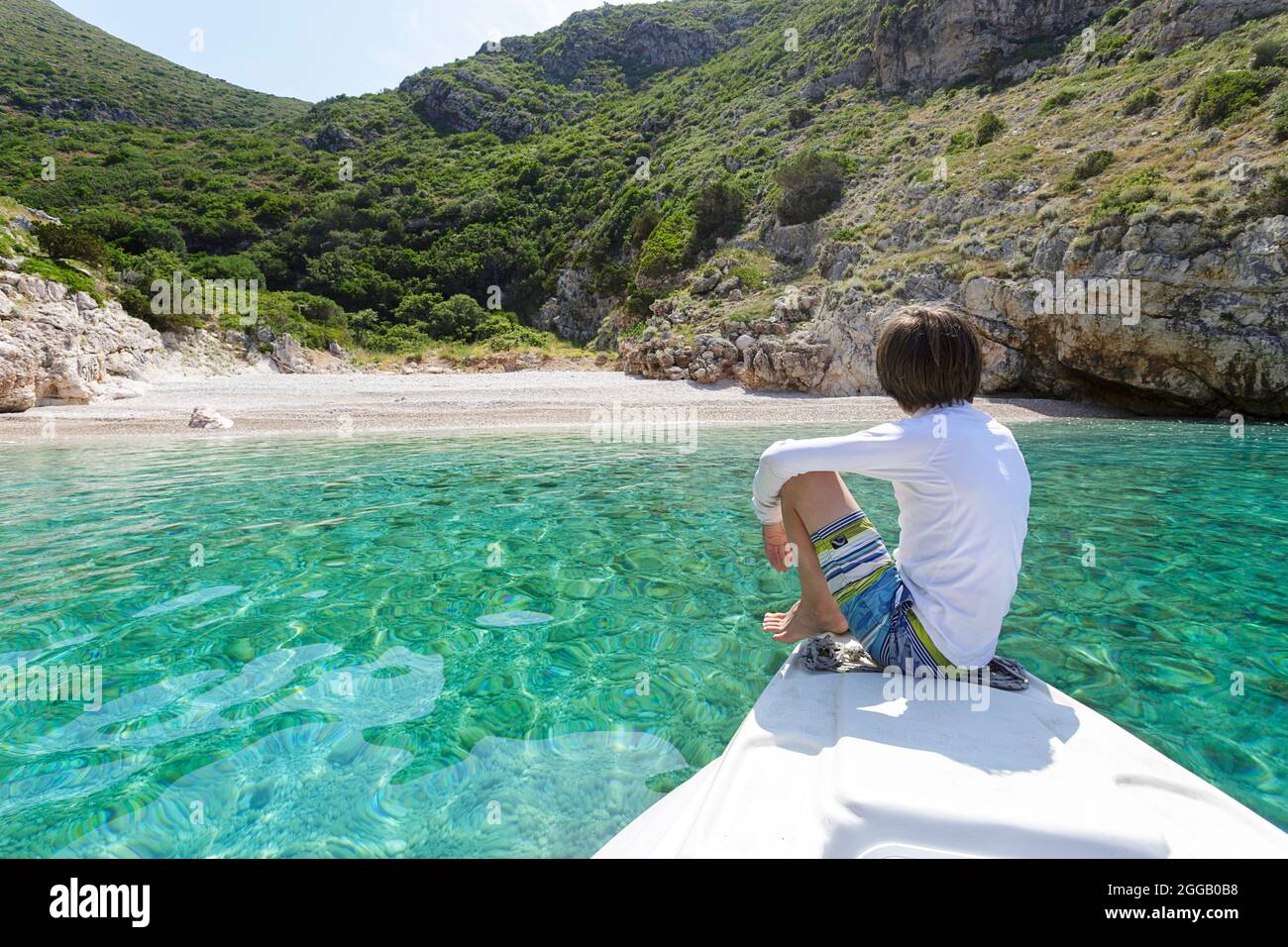 Ragazzo turistico seduto su un motoscafo mentre esplori spiagge isolate sulla penisola di Karaburun, albania Foto Stock