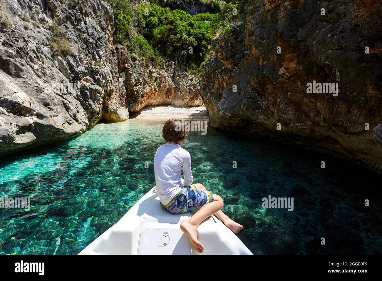 Ragazzo turistico seduto su un motoscafo mentre esplori spiagge isolate sulla penisola di Karaburun, albania Foto Stock