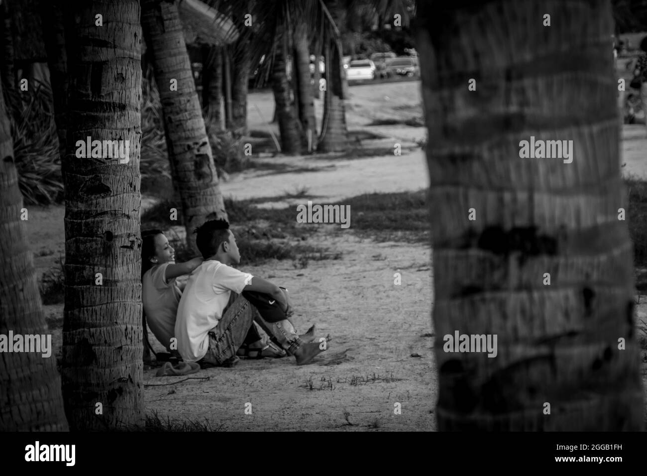 SUBIC, FILIPPINE - ago 01, 2017: Una vista in scala di grigi di una coppia filippina che risale seduta alla spiaggia di SMBA in Subic City, Filippine Foto Stock