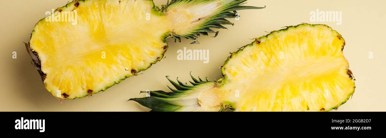 Ananas fresco tagliato in due parti e cornice di carta su sfondo giallo. Concetto estivo. Spazio creativo e piatto con spazio per la copia. Vista dall'alto. Foto Stock