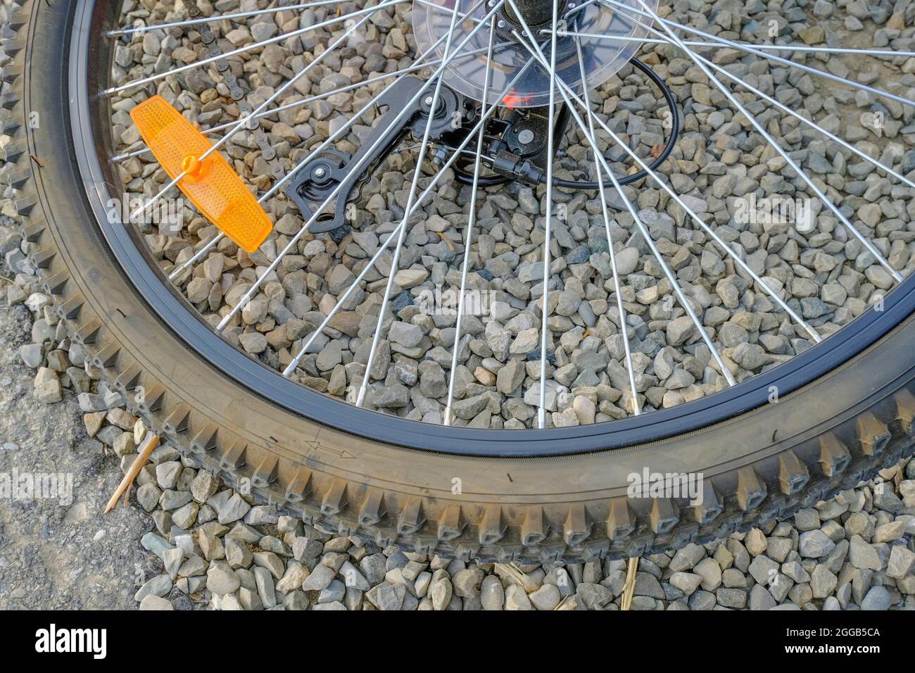 primo piano della ruota della bicicletta con catarifrangente arancione sullo sfondo in pietra. Dettaglio bicicletta. Pneumatico sgonfio Foto Stock