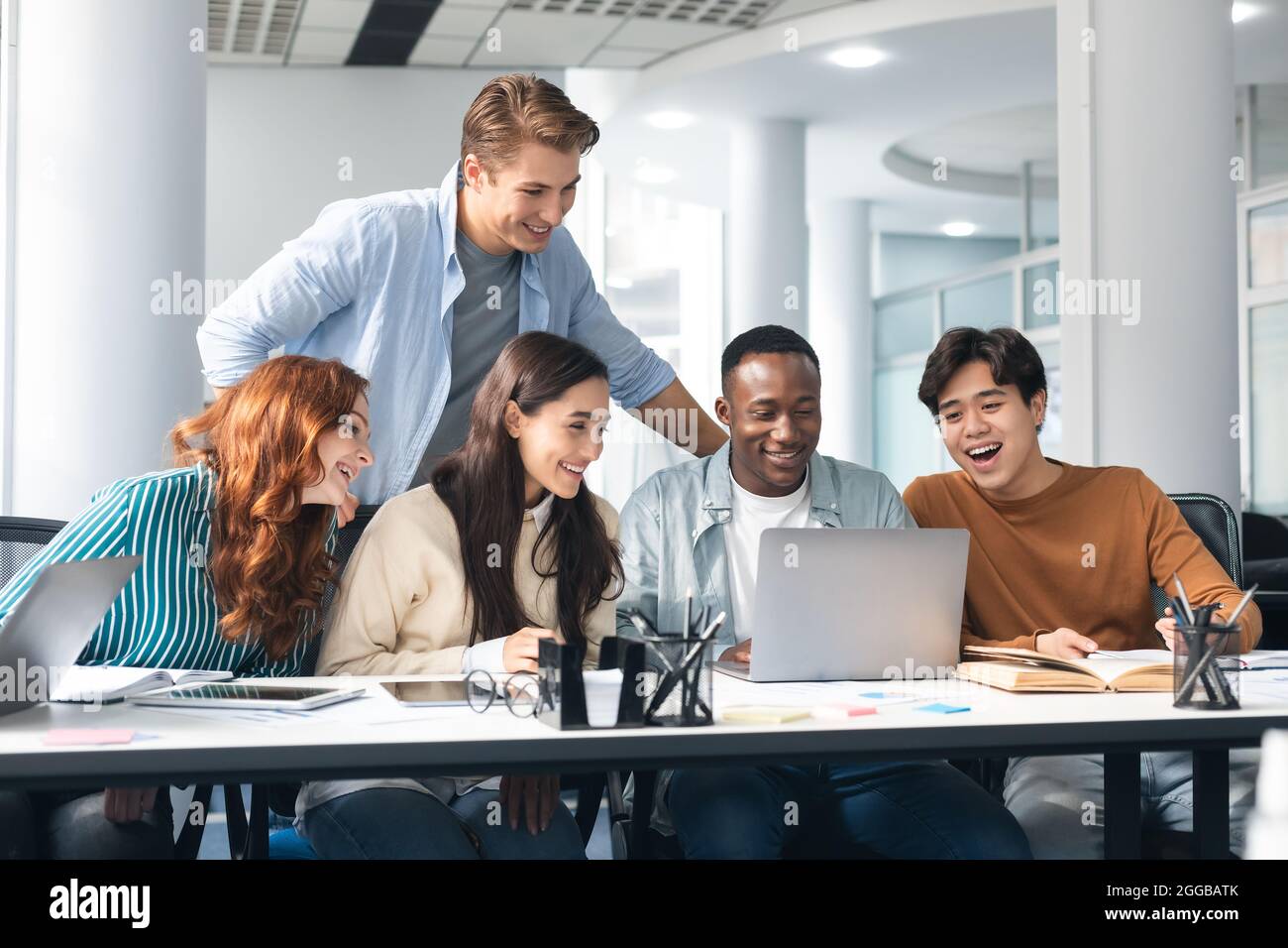 Gruppo di persone diverse che si siedono alla scrivania e utilizzano il pc Foto Stock