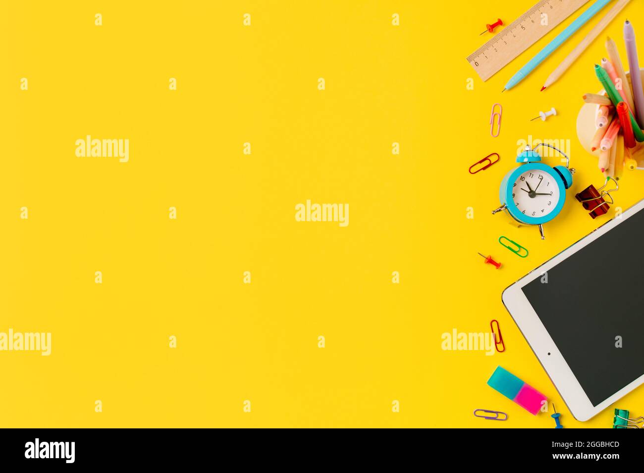 Ritorno a scuola, studio online, concetto di classe di apprendimento a distanza. Scrivania creativa per studenti con tablet pc e accessori colorati per scuole moderne su sfondo giallo. Vista dall'alto piana. Spazio di copia Foto Stock
