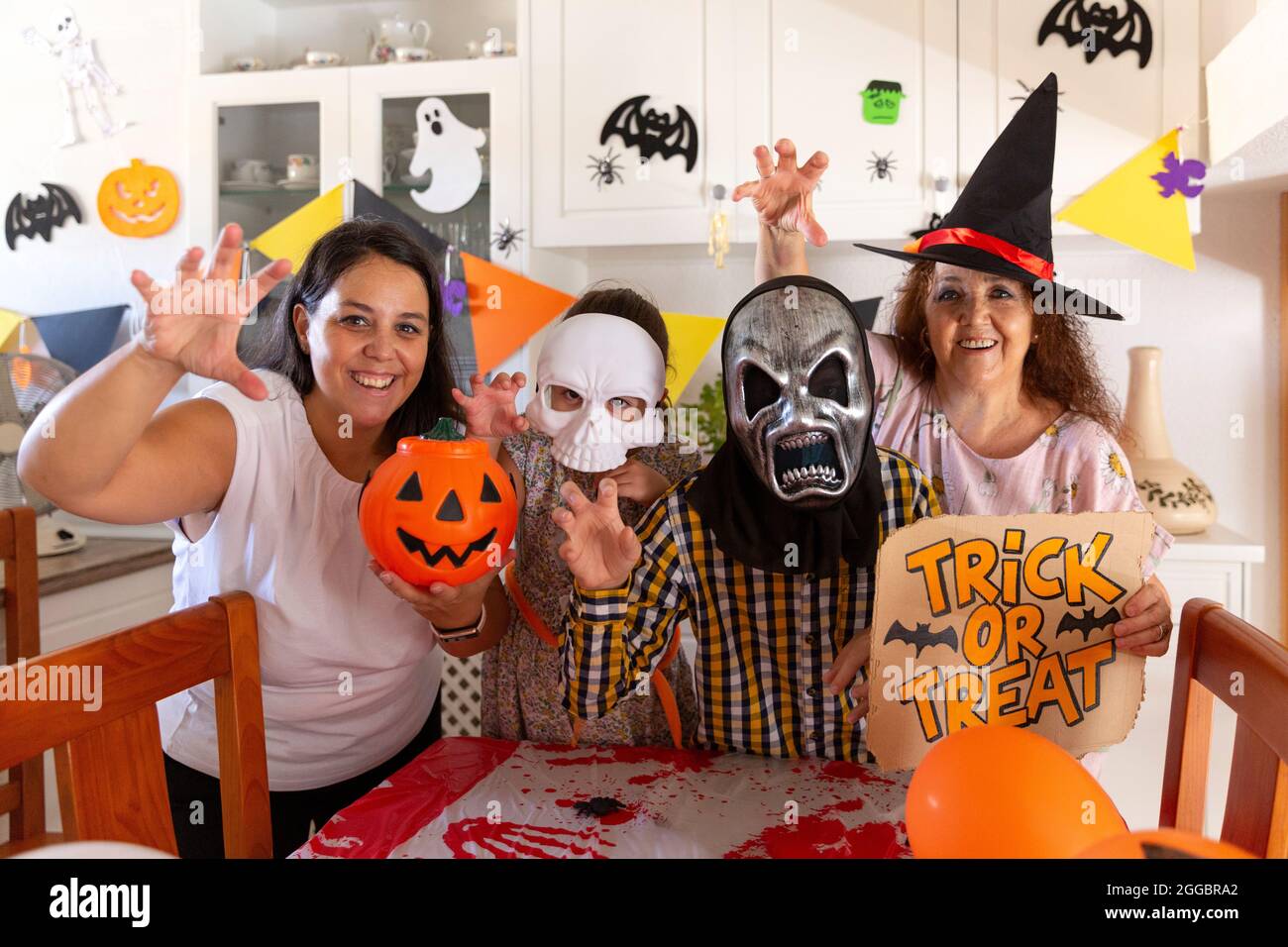 Famiglia in posa per una foto con un gesto minaccioso mentre festeggia la festa di Halloween a casa. Foto Stock