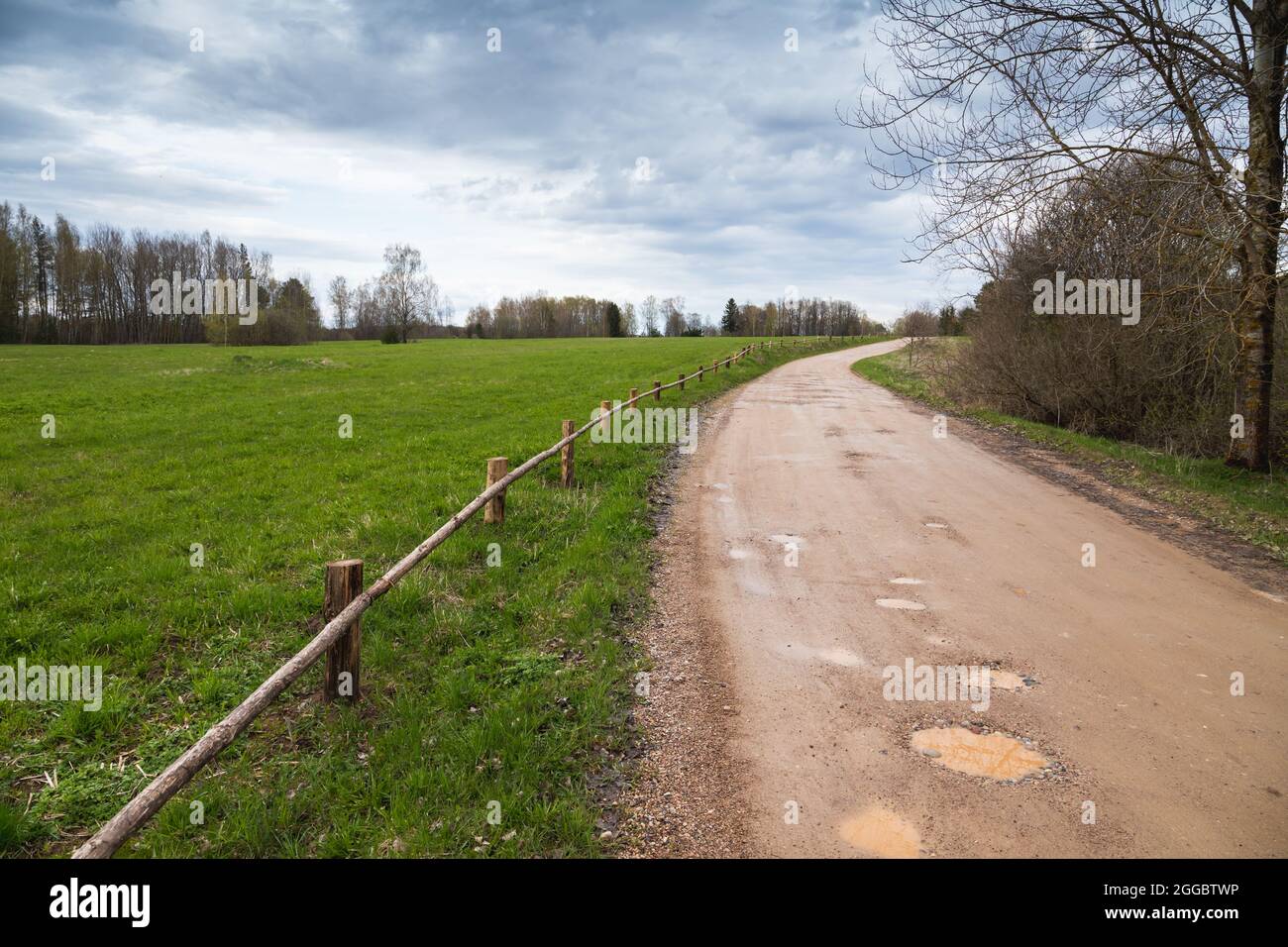 Strada rurale vuota girando con pozzanghere in primavera. Paesaggio russo Foto Stock