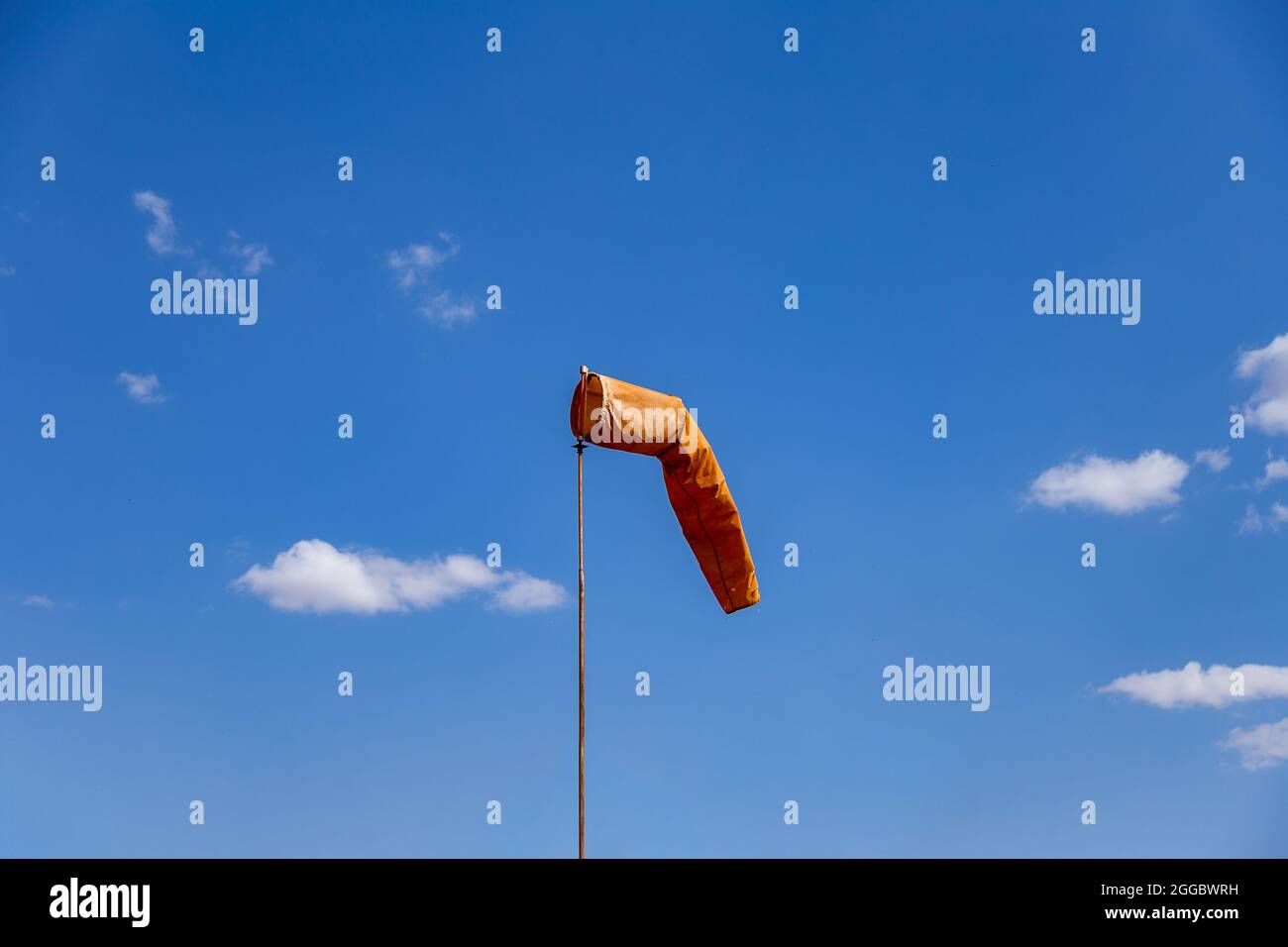 Calzino a vento che punta la posizione del vento. Calzino in arancione con cielo blu sullo sfondo, noto anche come 'Biruta de Vento' in portoghese. Foto Stock