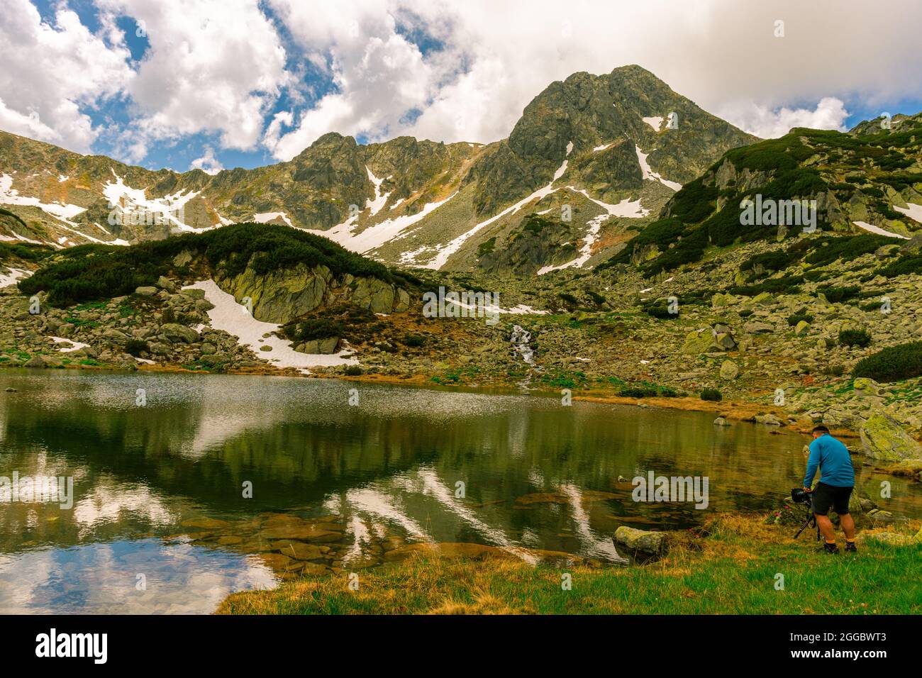 Bella fotografia paesaggistica di un lago di montagna con cime di montagna sullo sfondo. Il tempo è soleggiato con un paio di nuvole PF. Lago glaciale nel m. Foto Stock