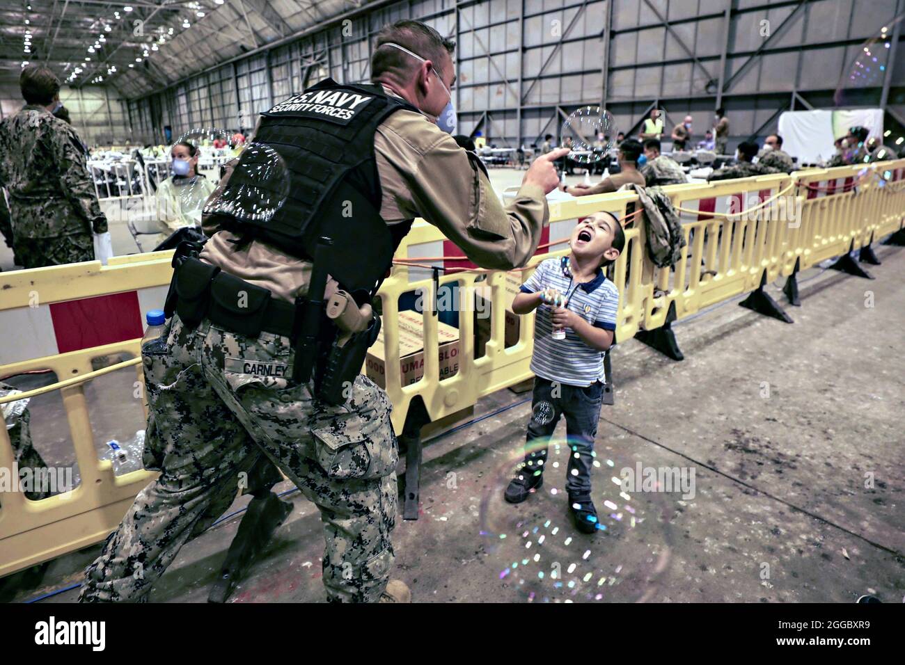 Rota, Spagna. 29 agosto 2021. Un marinaio della Marina degli Stati Uniti soffia delle bolle per un bambino afghano dopo l'evacuazione da Kabul alla base aeronavale Rota il 29 agosto 2021 a Rota, Spagna. NAS Rota fornisce alloggio temporaneo per gli sfollati dall'Afghanistan come parte dell'operazione Allees Refuge. Credit: Planetpix/Alamy Live News Foto Stock