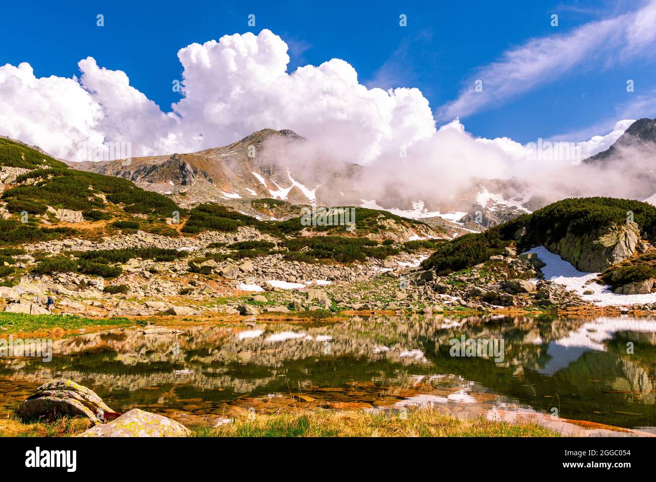 Bella fotografia paesaggistica di un lago di montagna con cime di montagna sullo sfondo. Il tempo è soleggiato con un paio di nuvole PF. Lago glaciale nel m. Foto Stock