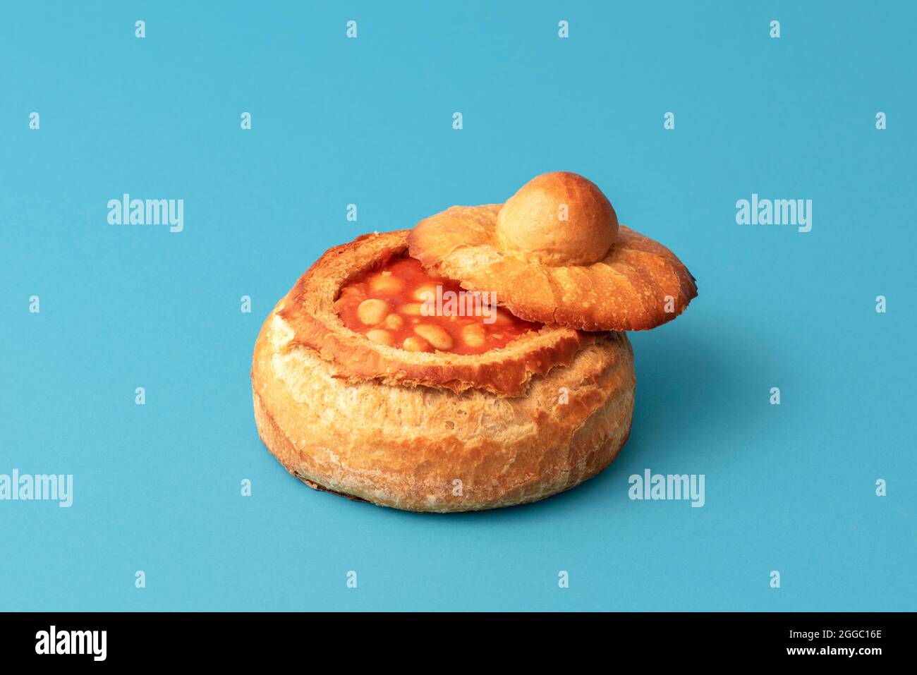 Piatto tradizionale con fagioli cotti in una ciotola a base di pane. Pane fatto in casa ripieno di fagioli cotti. Foto Stock