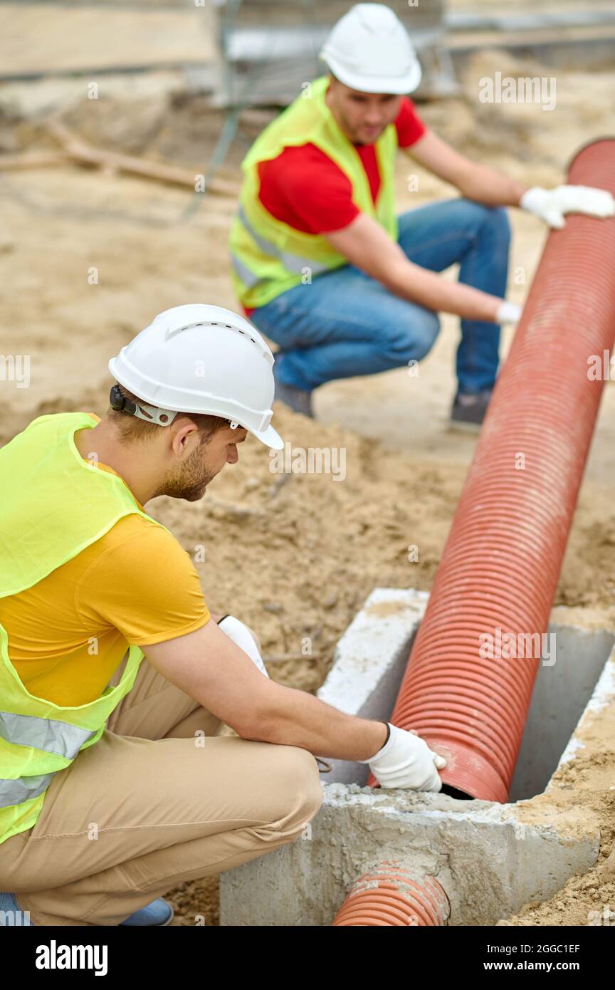 Due lavoratori esperti che installano una linea fognaria residenziale Foto Stock