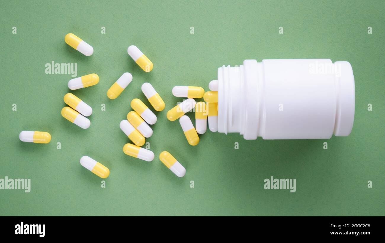 Le pillole sono sparse sul tavolo. Compresse su sfondo verde. Compresse medicinali, capsule, pillole. Foto Stock