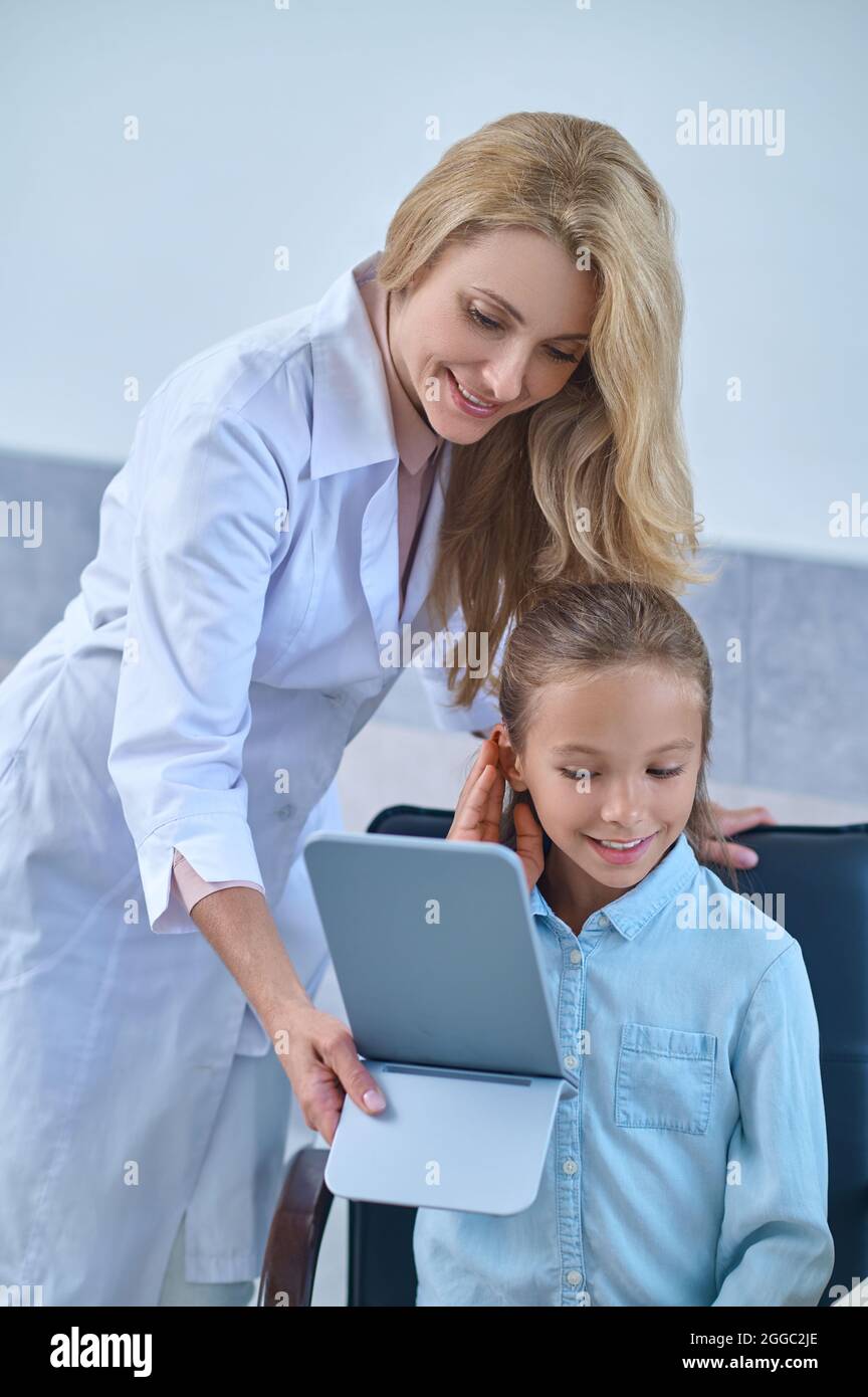 Sorridendo il giovane paziente che sta cercando un nuovo apparecchio acustico Foto Stock