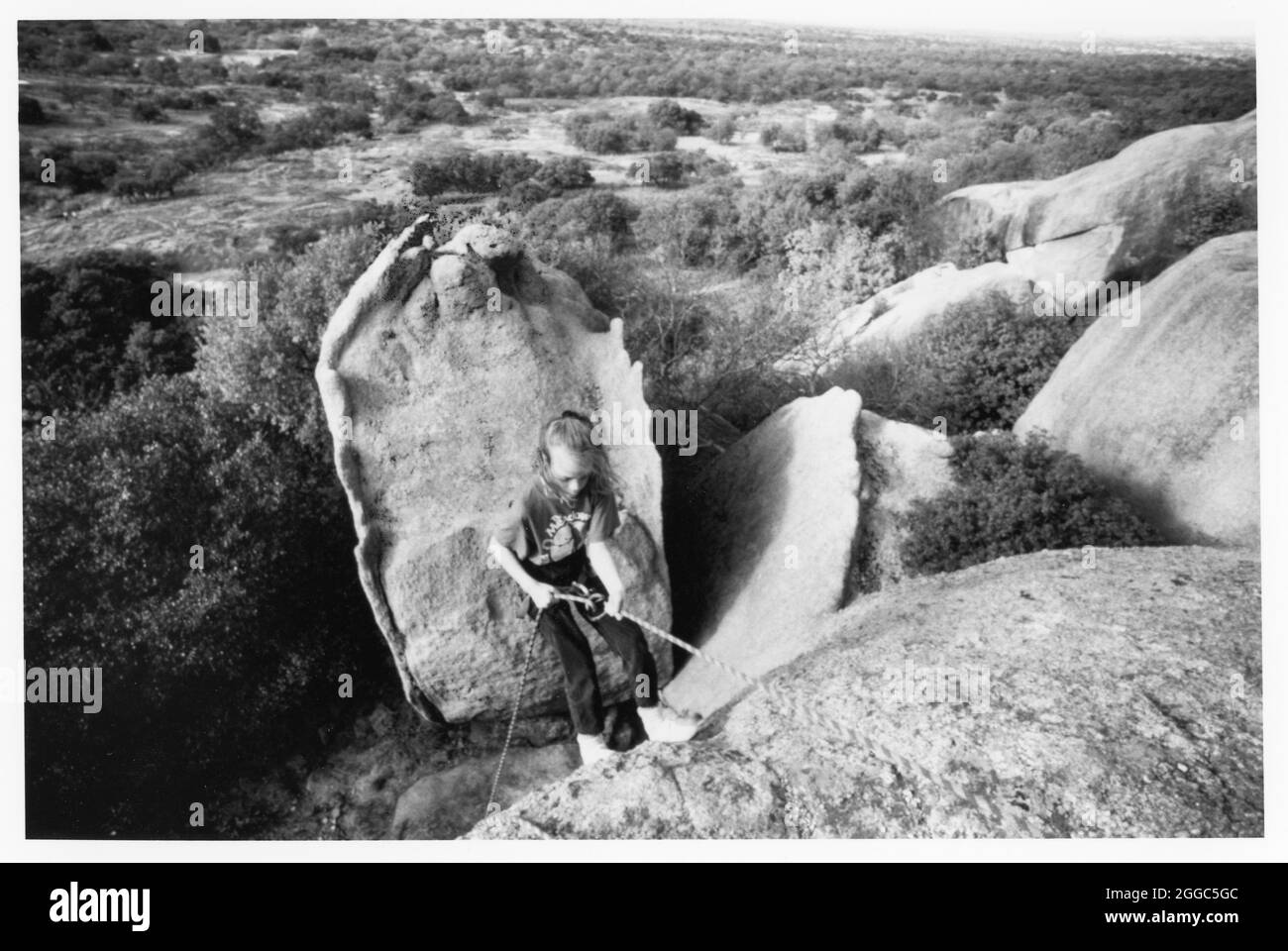 Circa1990's: Bambina di nove anni scende oltre 70 metri di scogliera all'Enchanted Rock State Park vicino Fredericksburg, Texas. (Originale a colori) ©Bob Daemmrich Foto Stock