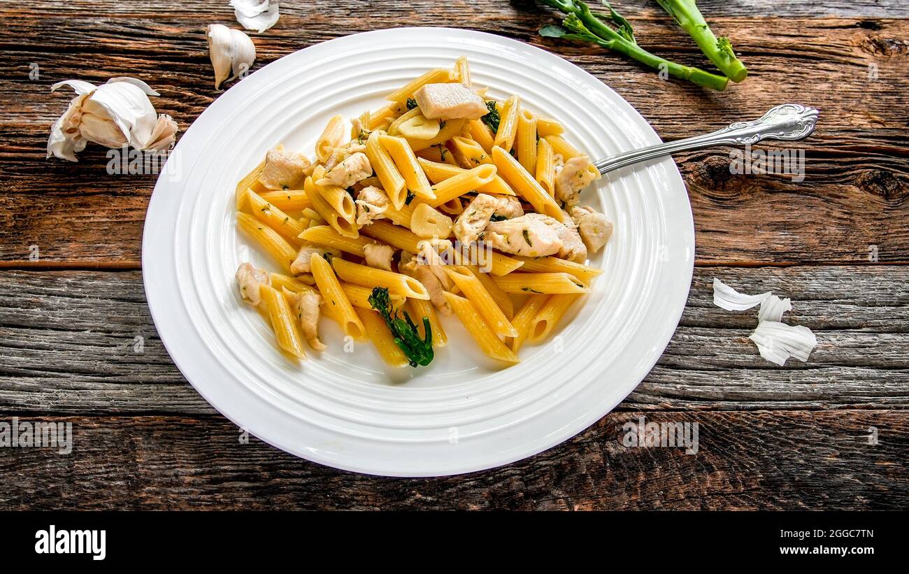 Penne pasta con pollo, aglio e broccoli su tavola rustica di legno dall'alto Foto Stock