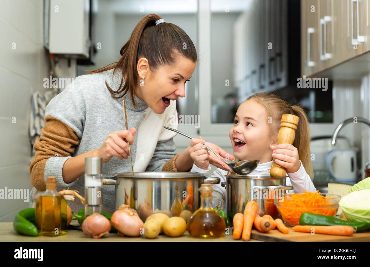 Madre emozionale e piccola figlia degustazione zuppa insieme Foto Stock