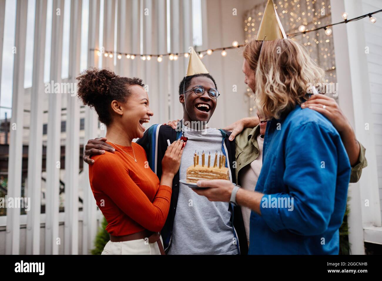 Ritratto vita su gruppo vario di amici che festeggia il compleanno al partito del tetto e tenendo la torta con le candele, spazio di copia Foto Stock