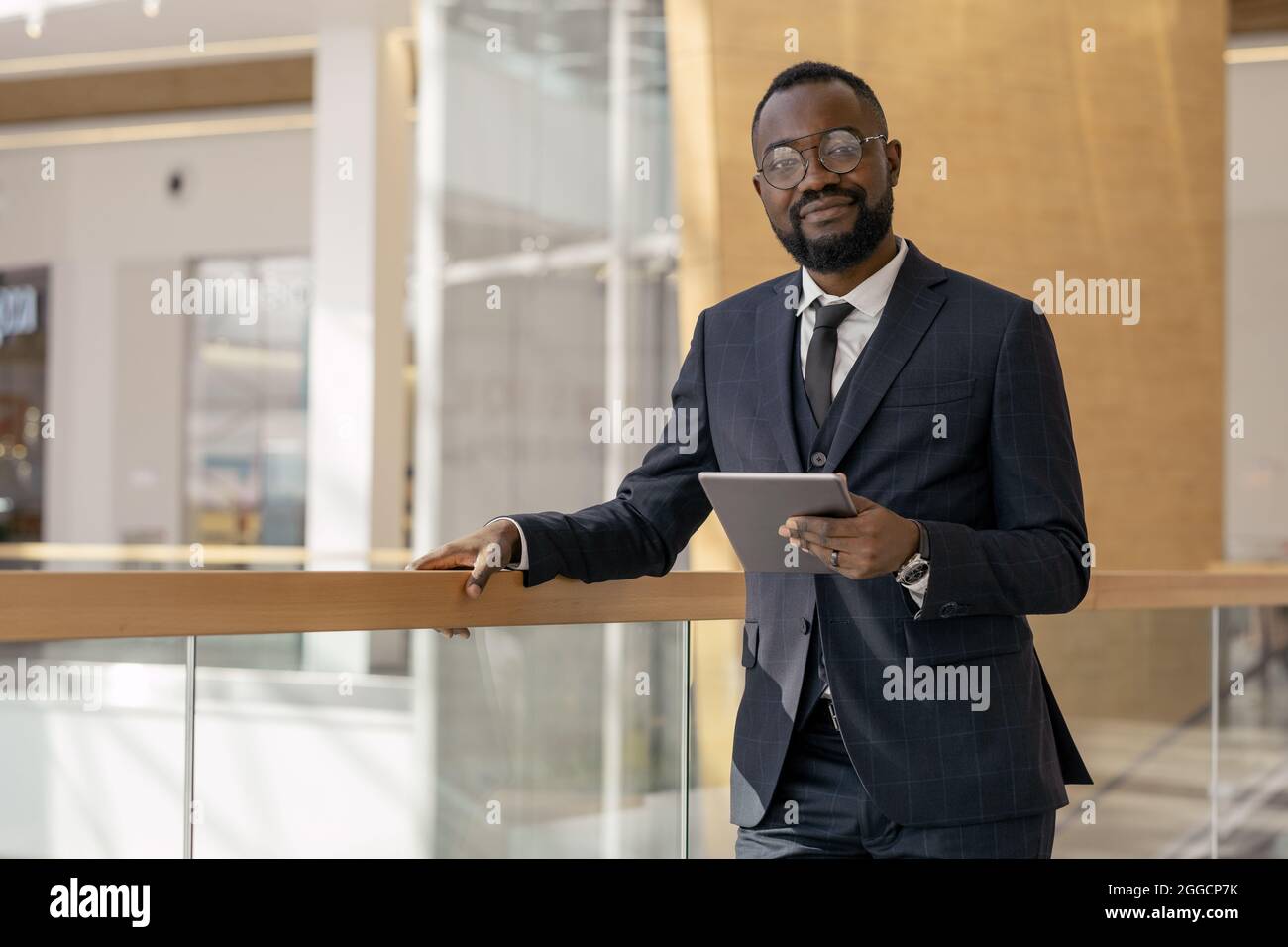 Giovane dipendente africano di successo con un tablet che ti guarda mentre ti trovi all'interno del business center Foto Stock