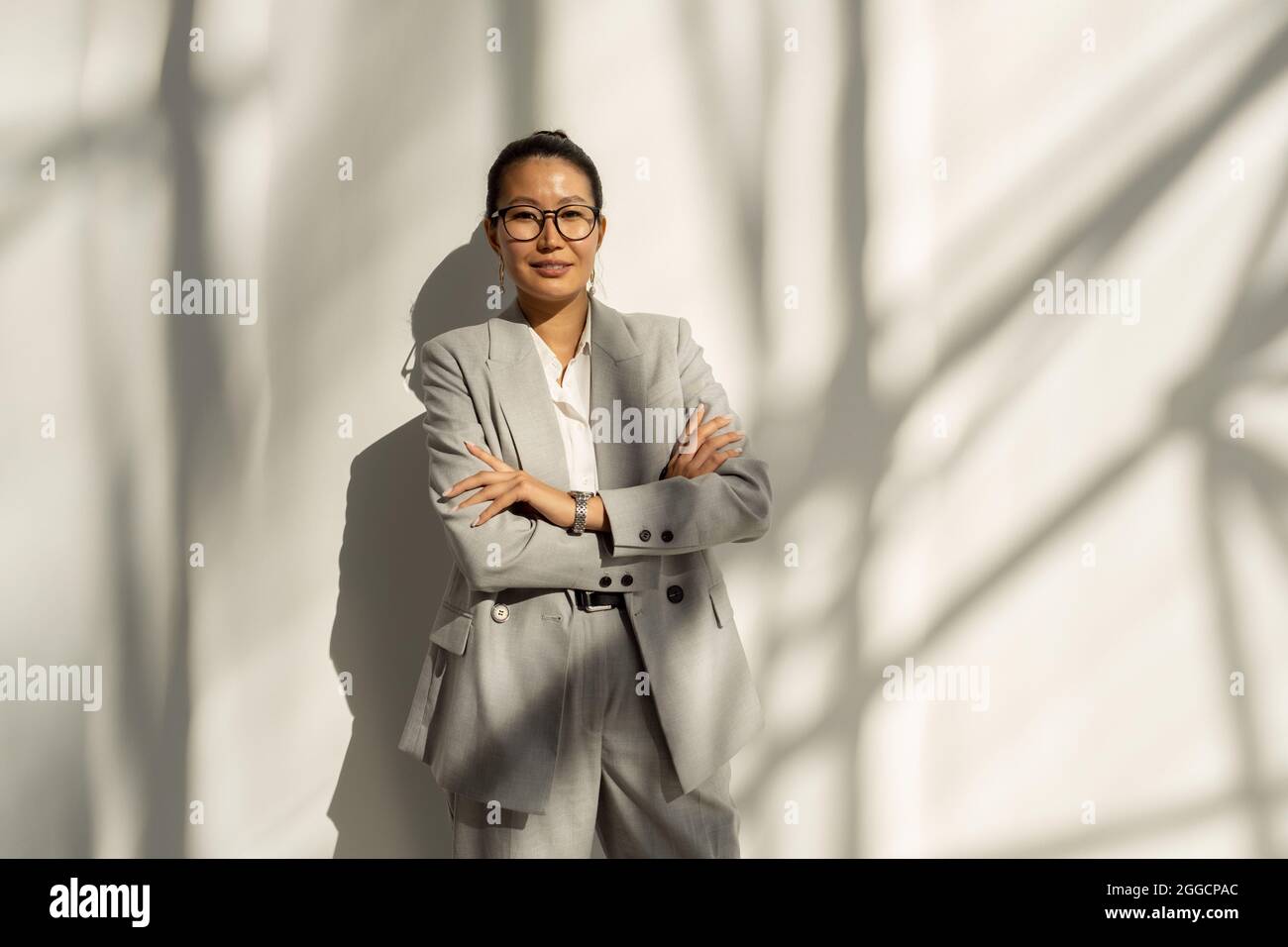 Giovane donna asiatica in abito elegante che le attraversa le braccia al petto Foto Stock