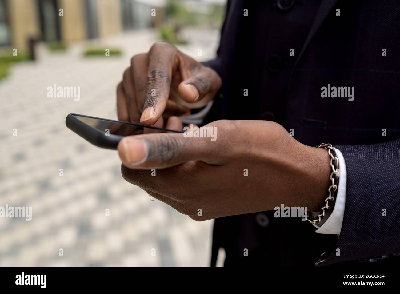 Mani di un uomo d'affari africano che puntano allo schermo dello smartphone davanti alla fotocamera Foto Stock