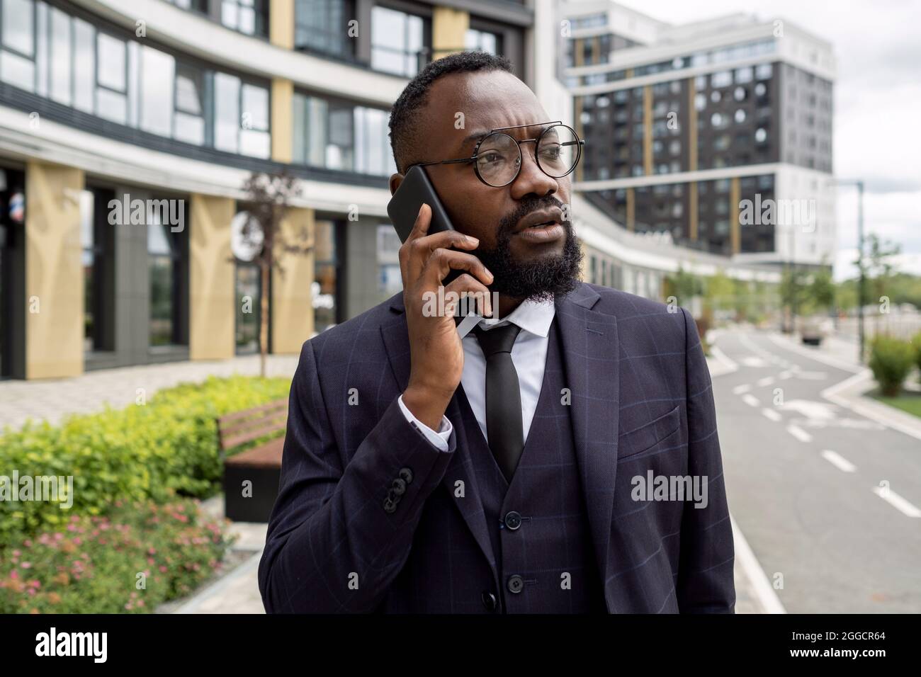 Mediatore giovane e sicuro con smartphone da parte del cliente di consulenza EAR mentre si sposta in ambiente urbano Foto Stock