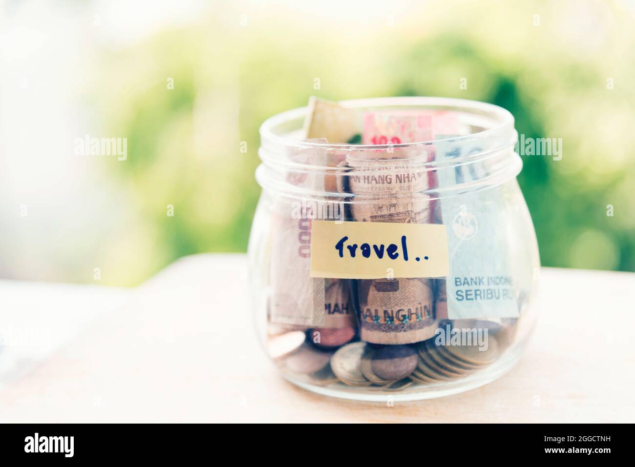 Risparmio di denaro per il concetto di vaso da viaggio. Cassa di denaro su tavola vuota raccogliere banconote e monete per il budget di viaggio di vacanza. Foto Stock