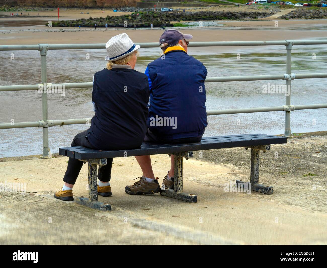 L'uomo e una donna si riposano su una panchina che si affaccia sul mare a Skinningrove Foto Stock