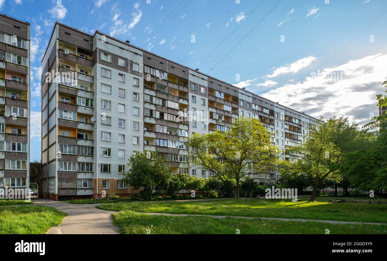 Facciata di un edificio residenziale a pannelli a più piani a riga, Lettonia. Tipica architettura urbana post-sovietica. Albero verde in cortile. Foto Stock