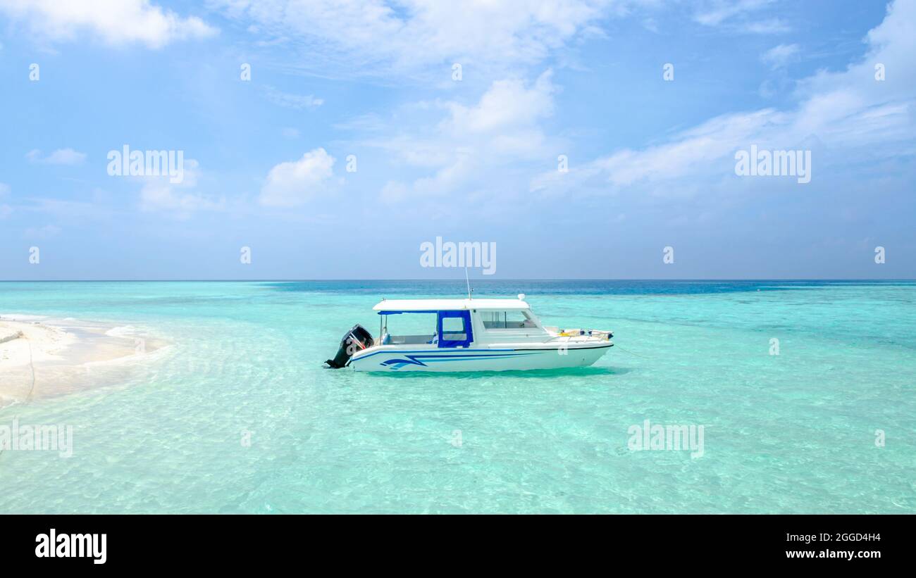 Un motoscafo che galleggia sulle acque cristalline di una spiaggia dell'isola delle Maldive Foto Stock