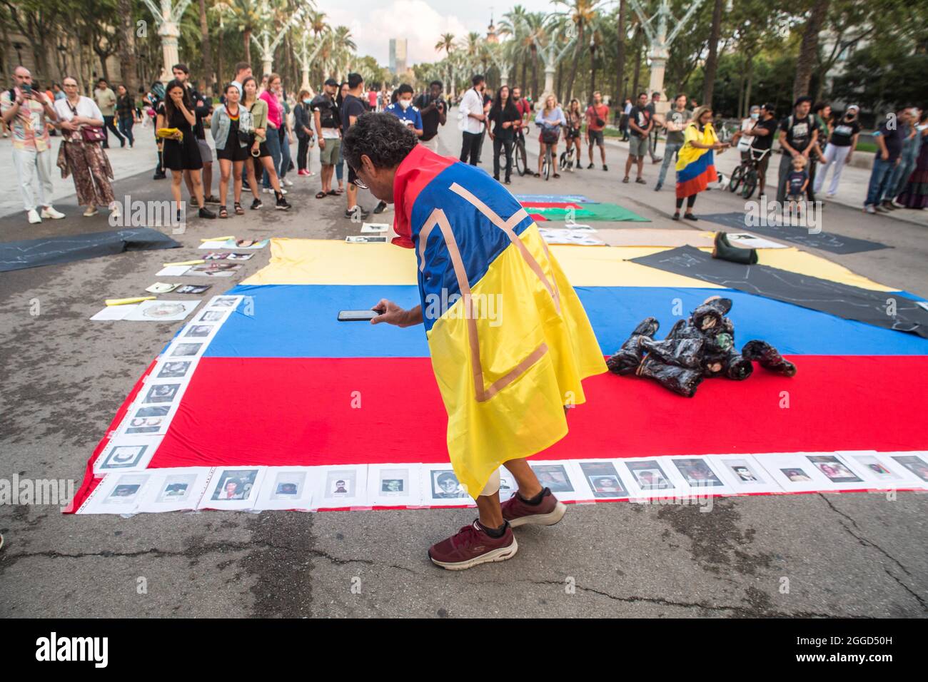 Barcellona, Spagna. 30 Agosto 2021. Il manifestante è visto con la bandiera colombiana sulla sua schiena. Circa 200 persone hanno dimostrato di fronte all'Arc de Triomf di Barcellona contro le 6402 uccisioni extragiudiziali commesse dall'esercito nel contesto del conflitto armato colombiano, un fenomeno noto come "falsi positivi”. La manifestazione si è svolta in occasione della Giornata Internazionale delle vittime della sparizione forzata, commemorata ogni 30 agosto e cui hanno partecipato Ricardo 'Profe', una delle prime linee di difesa, nelle proteste anti-governative. Credit: DAX Images/al Foto Stock