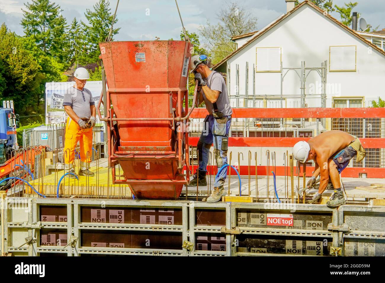 I costruttori versano calcestruzzo nella cassaforma del muro. Progetto di costruzione di appartamenti a Riehen, Basilea, Svizzera. Foto Stock