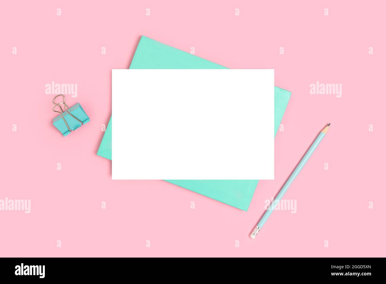 Carta bianca mockup e cancelleria su sfondo rosa. Spazio di lavoro scolastico minimalista. Foto Stock