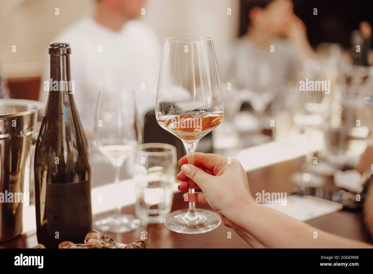 Bicchieri con diversi tipi di vino e mani umane che tengono i bicchieri da vino sullo sfondo. Degustazione di vini Foto Stock